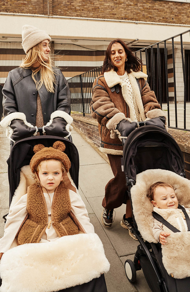 Två föräldrar kör barnvagnar med Buggy Mittens och åkpåsar i fårskinn från Binibamba
